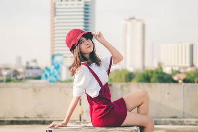 Young woman wearing hat sitting in city