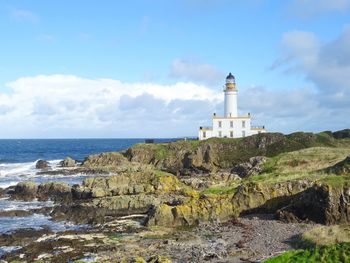 Lighthouse amidst sea and buildings against sky