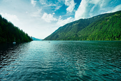 Scenic view of lake by mountains against sky