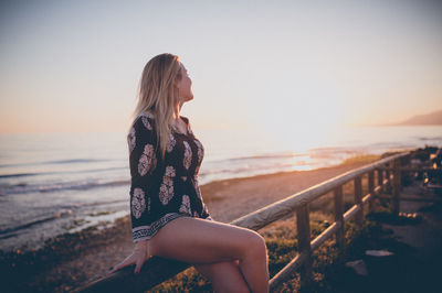 Woman on beach against clear sky during sunset