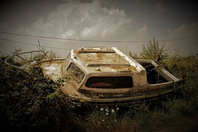 Abandoned car on field against sky