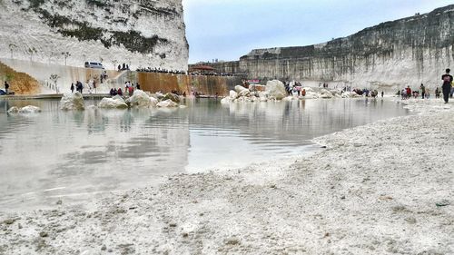 People on shore against sky