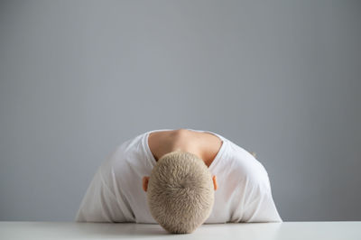 Rear view of man relaxing against wall