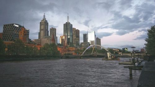 City at waterfront against cloudy sky