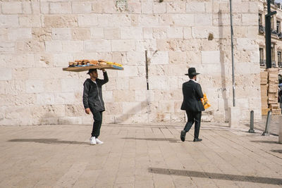 Full length rear view of man walking on footpath