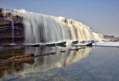 Scenic view of waterfall against sky