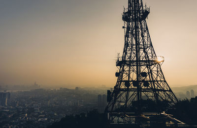 Silhouette communications tower against sky at sunset