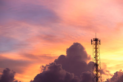 Low angle view of electricity pylon against sky during sunset