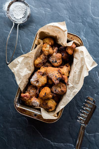 A baking pan lined with parchment paper filled with deep fried fritters.