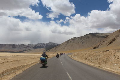 People riding motorcycle on road against sky