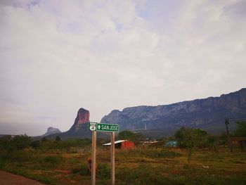 Road sign by mountains against sky