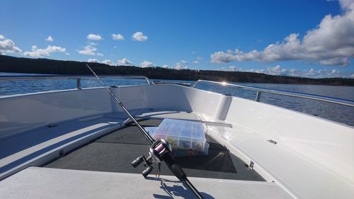 Fishing rod in sailboat on sea against sky