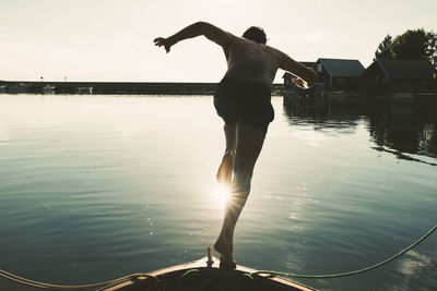 Full length of shirtless man diving into lake from boat on sunny day