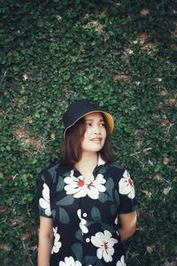 Portrait of smiling young woman standing against plants