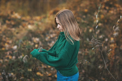 Portrait of a beautiful teenage girl with blond hair and blue eyes in an autumn park.