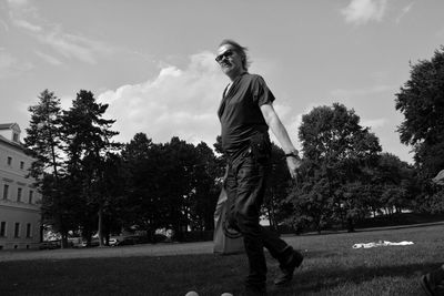 Side view of young man standing against trees