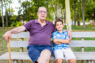 Grandfather and his grandson sitting on a bench in the park