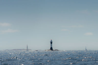 Lighthouse by sea against sky