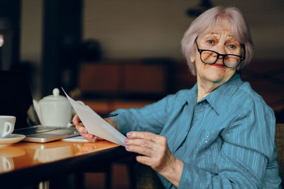 Portrait of senior businesswoman holding document in cafe