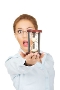Young businesswoman holding hourglass against white background