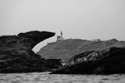 Lighthouse by sea against clear sky