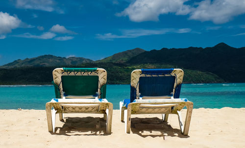 Chairs on beach against blue sky