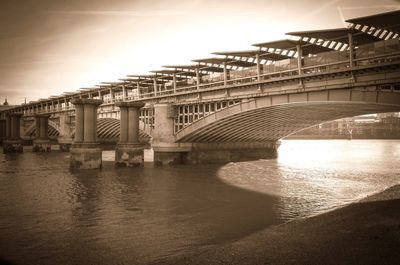 Bridge over river in city against sky