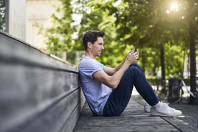 Man sitting on bench using smartphone