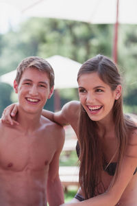 Portrait of cheerful shirtless man with girlfriend at park