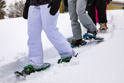 Low section of people walking on snow