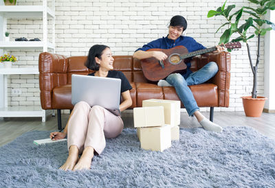 Full length of a young couple sitting on guitar
