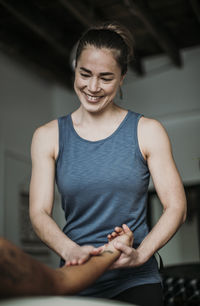 Smiling massage therapist treats her patient's hand and arm