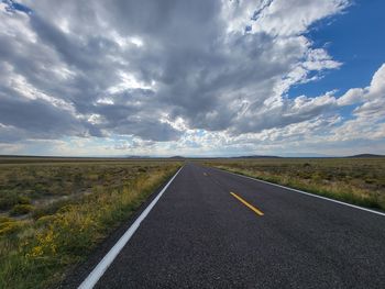 Surface level of empty road against cloudy sky