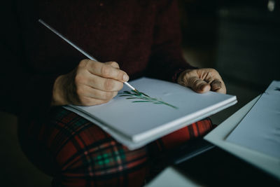 Midsection of man holding paper on table