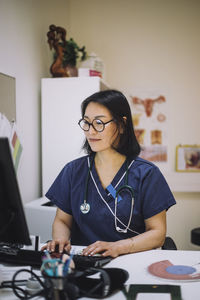 Smiling female healthcare expert using computer sitting at desk in office