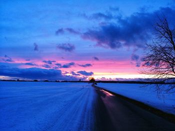 Road by sea against sky at sunset