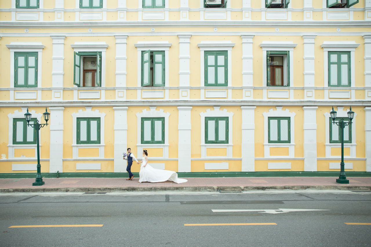 architecture, building exterior, city, built structure, facade, road, street, full length, day, transportation, neighbourhood, building, window, residential area, one person, downtown, adult, urban area, road marking, women, outdoors, side view, sign, men, marking