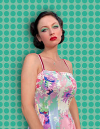 Portrait of young woman standing against wall
