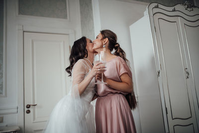 Woman with mother and daughter standing against wall