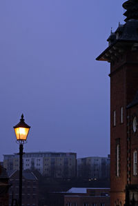 Illuminated street light against clear blue sky