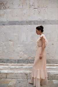 Side view of woman standing against wall