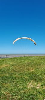 Scenic view of field against clear blue sky paragliding