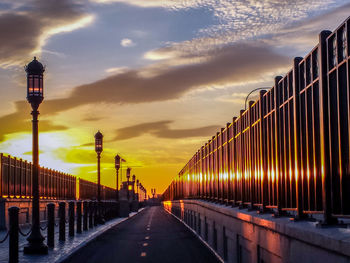 Empty road against cloudy sky during sunset