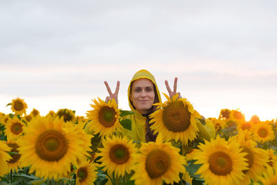 Portrait of woman with sunflowers on field against sky