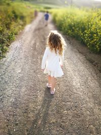 Rear view of woman walking on road