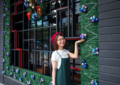 Portrait of smiling young woman touching christmas decoration