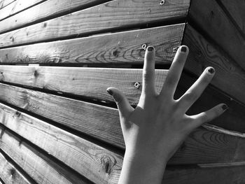 Close-up of human hand on wooden wall