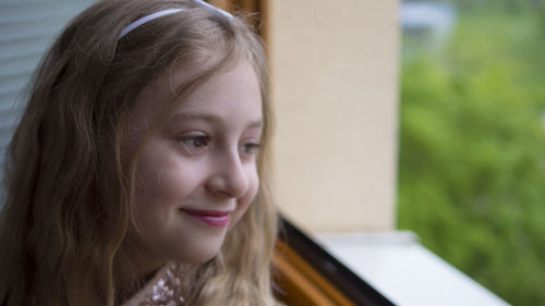 Close-up of thoughtful girl looking through window