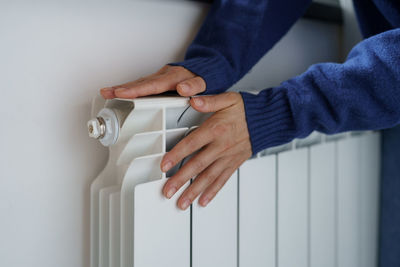 Closeup of woman warming her hands on the heater at home during cold winter days. heating season.