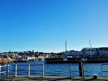 Boats moored at harbor against clear blue sky